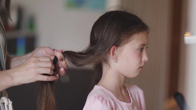 Mom braids and comb a little upset daughter.