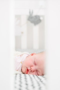 Sleeping baby viewed through the cot bars