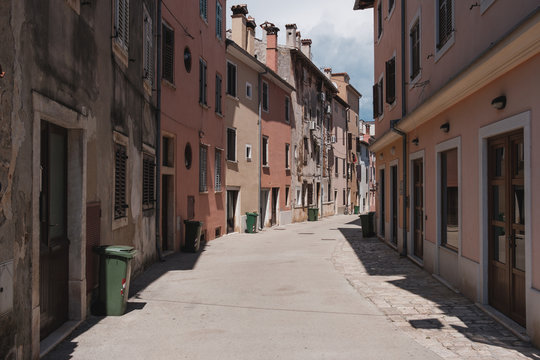 Empty Mediterranean Alley With Green Garbage Bins