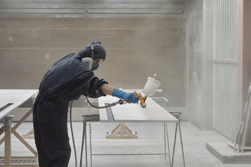 Carpenter Spraying Finish On Wood