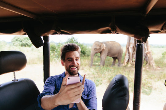 Man Taking Selfie On Safari With Elephant In Background