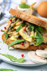 Sandwich with omelet, greens and mushrooms close-up.
