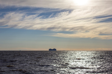 modern white cruise liner in the sea under the evening rain clouds, view from the water