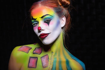 Nice young woman with a face painting clown.