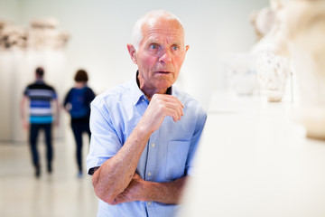 Mature man visiting sculptures exhibition