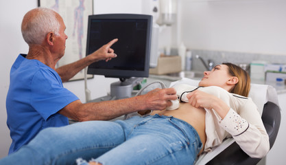 Pregnant woman undergoing ultrasound test by senior man doctor