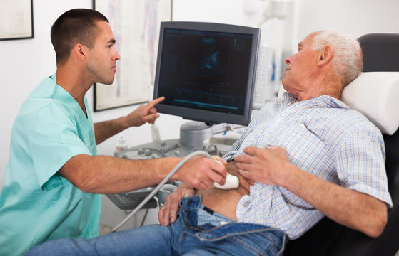 Man sonographer examining male patient