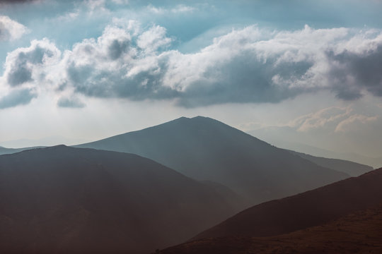 Landscape with sunset clouds between mountains.