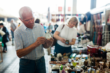 Loving senior family couple choosing vintage things on street market
