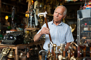 Fototapeta na wymiar Elderly man chooses rare walking stick at street market