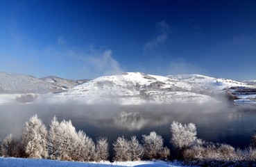 A lake near a hill covered with snow