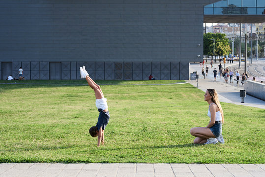 Blonde girl doing handstand with sister watching.