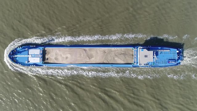 Aerial top down view of a barge a flat-bottomed ship built mainly for river and canal transport of heavy goods and bulk materials in this case the vessel is carrying sand stable footage 4k quality