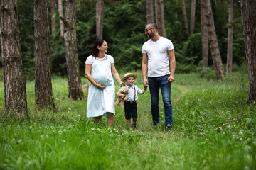 Naklejka na ściany i meble Pregnant young woman with her family in nature