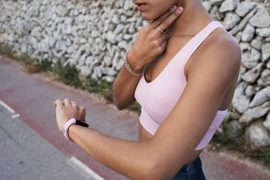 Crop of athlete measuring pulse using smart band watch.