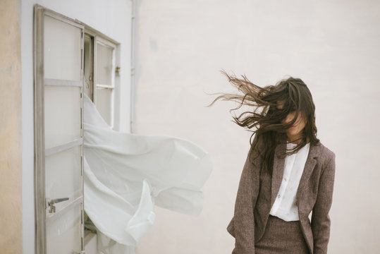 Young woman with tousled hair standing in wind