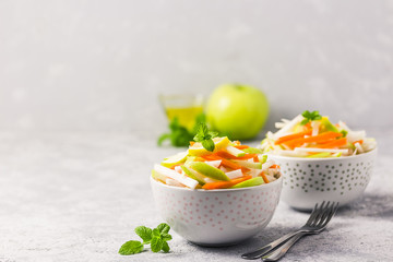 Detox turnip, carrot, apple salad in bowls with olive oil dressing. Selective focus, space for text.