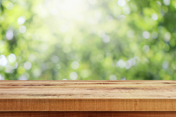 Blurred abstract green bokeh and wooden table background.