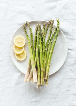 Roasted asparagus, lemon, garlic on ceramic plate and linen tablecloth