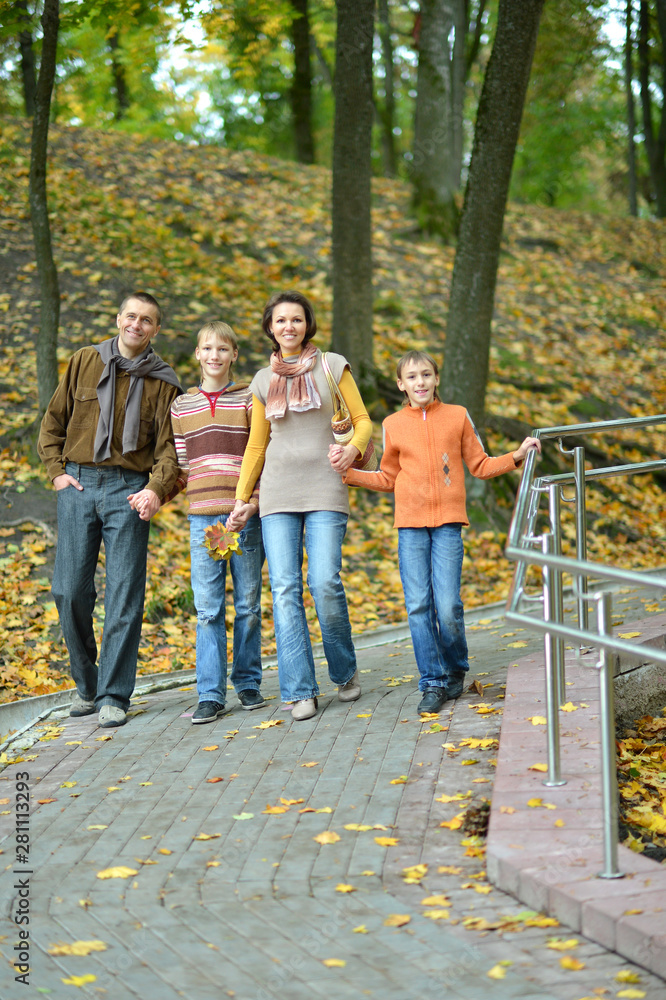 Wall mural Family of four walking in autumn park