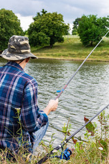 Fisherman fishes on the lake, fisherman man near the water with a fishing rod on a quiet calm evening