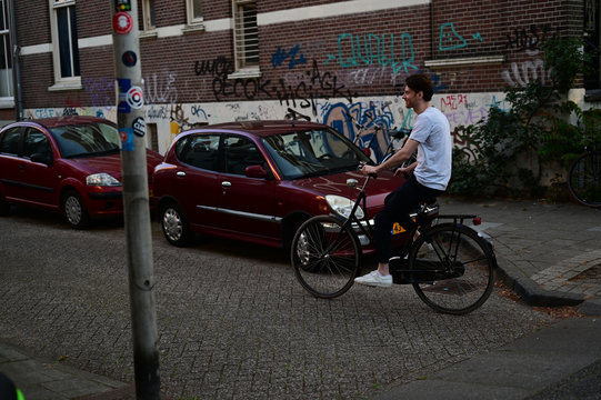 Dutch student riding on his bicycle through an old Dutch street with grafitti on the walls