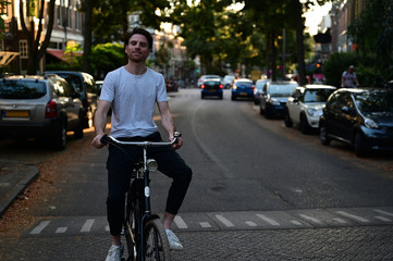 Smiling Dutch student riding home on his bicycle after a long day of studying at the university