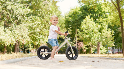 Cute little boy on bike, bicycle in the yard. Healthy lifestyle of children