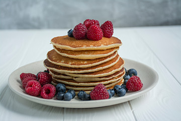Classic American pancakes with fresh berry on a blue wooden background. Pancakes with fruit. Summer homemade breakfast.