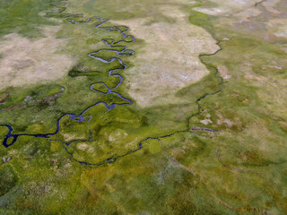Aerial top view of green land and small curve river in Aspen Springs, Mono County California, USA
