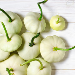 Young white patisons with green tails lie on a wooden table