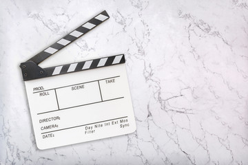Open clapboard on white marble background. White clapper board with space for your copy. Flat lay. Top view