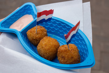 Traditional dutch street food decorated with holland flags. Fried fish balls in plate with napkins and decoration. Tasty snack in Amsterdam. Street cuisine. 