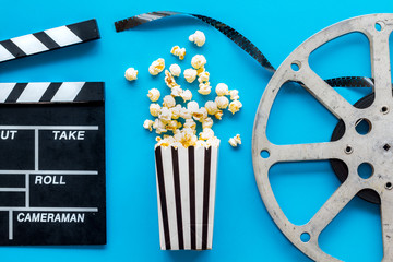 Go to the cinema with popcorn, film type and clapperboard on blue background top view
