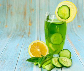  A glass of healthy green juice from cucumber and lemon, decorated with basil leaves. Concept of diet. Useful summer refreshing drink for weight loss. Copy space