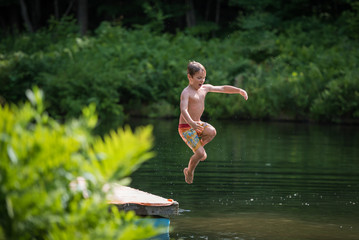 Timeless summer fun child jumping from dock into pond 