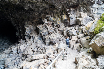 Woman cave explorer hikes down into the Skull Cave in Lava Beds National Monument in California