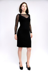 Fototapeta premium Horizontal Portrait of a pretty slim beautiful fashionable adult girl with beautiful brunette hair in a black dress. It should be in full growth, talking showing different poses and emotions