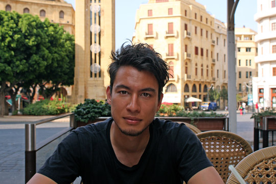 Young man with wild dark hair in a cafe looking at the camera