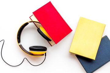 Listening audio books with headphones in library on wooden background top view