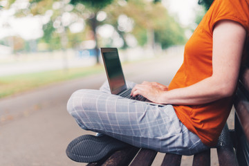 Naklejka premium Woman using laptop computer on park bench