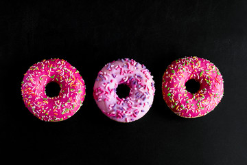 top view pink berry doughnuts row on a black background