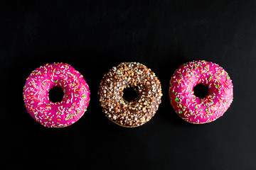 top view flat lay berry and chocolate doughnuts on a black background
