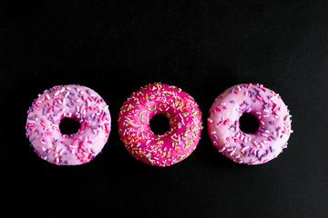 top view pink berry doughnuts row on a black background