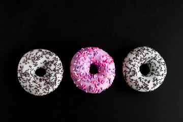 top view white and pink doughnuts on a black background