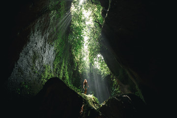 Young girl Girl stands under the ray of light in the cave  in Bali,  indonesia. Tukad Cepung...