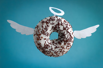sweet donut with white paper wings and nimbus on a  blue background