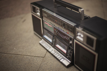 The retro boombox, an outdated portable radio with a cassette recorder from the 80s, stands on the...