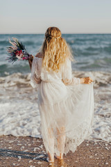 Fototapeta na wymiar The bride standing by the sea and the flowers in her hand