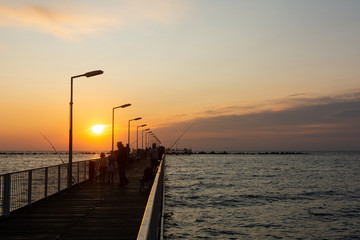 Fototapeta na wymiar Fishermen on pontoon bridge in the golden hours of sunrise